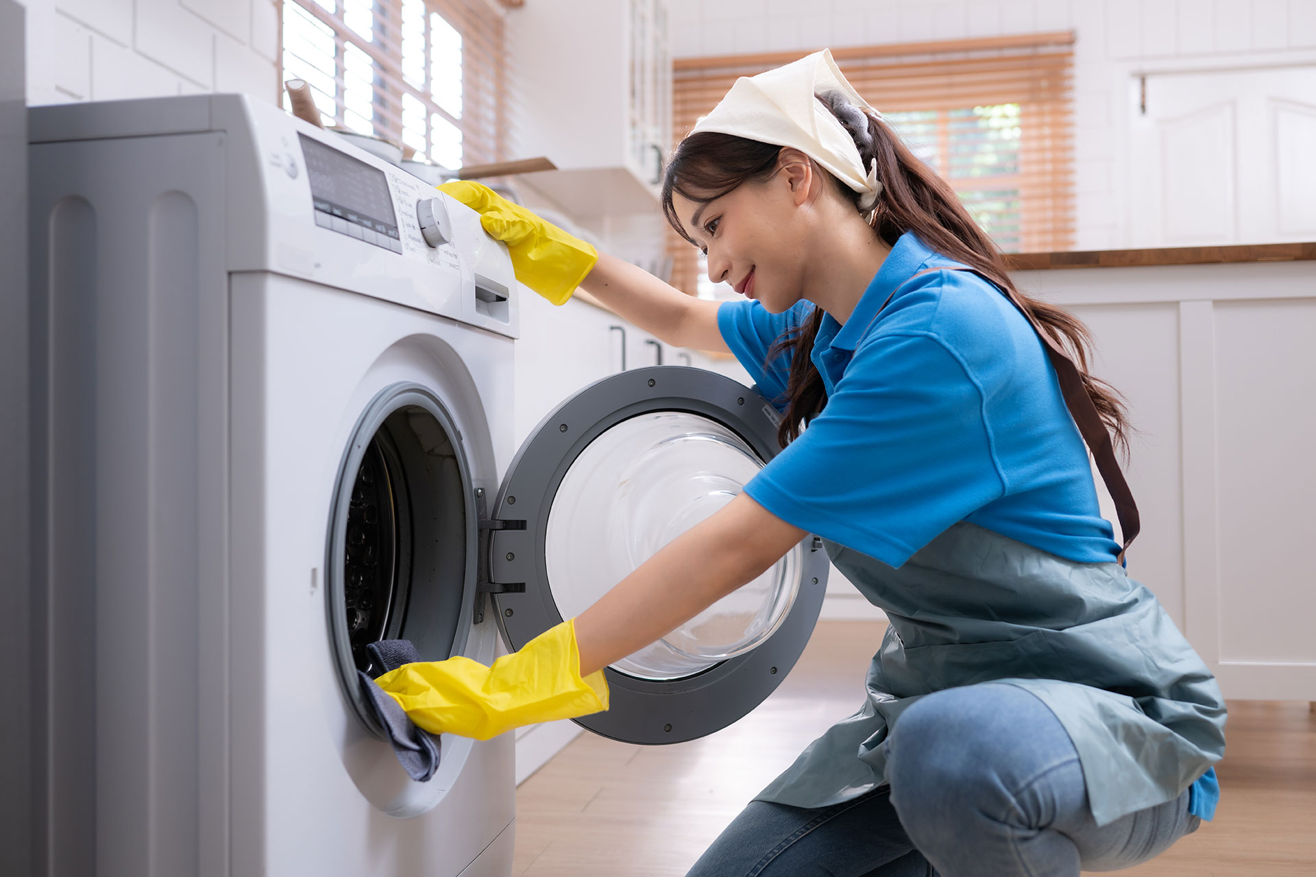 A woman cleaning the inside of a washing machine.